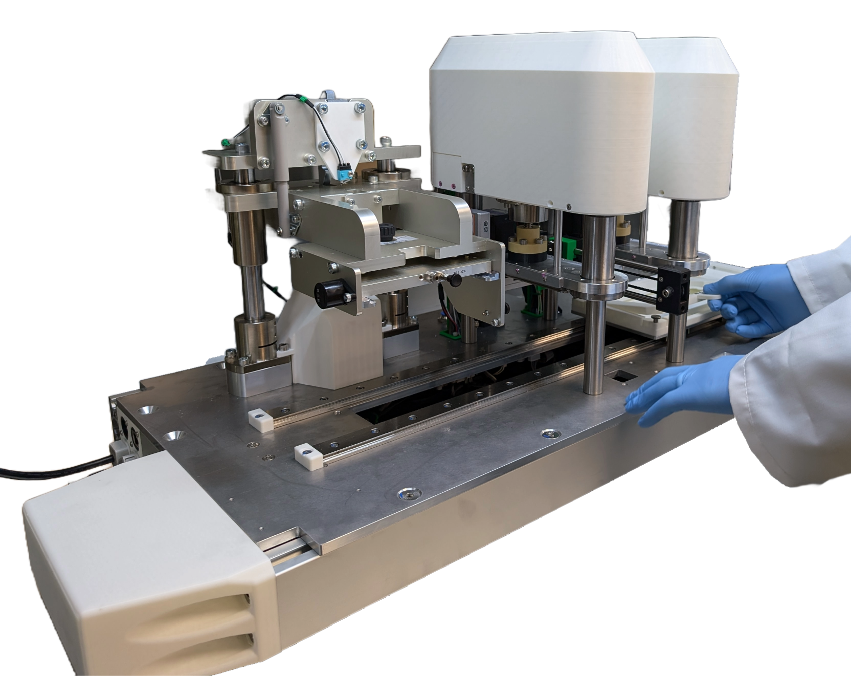 Laboratory technician wearing blue gloves adjusting a metal and plastic automated laboratory device on a workbench.