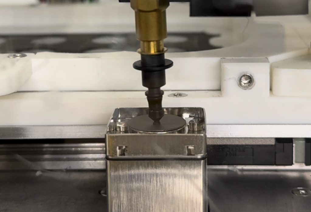 Close-up of a precision weighing machine measuring a small round disc.