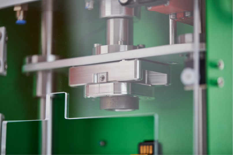 Close-up view of a metal sealing machine component with a green background.