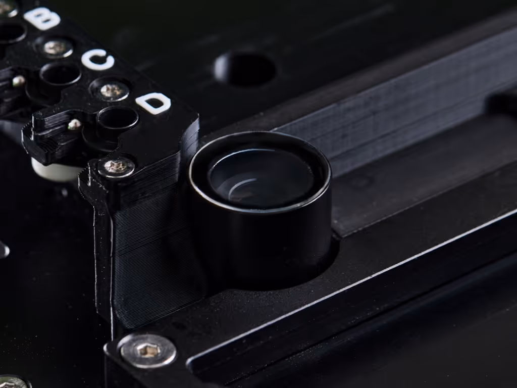 Close-up of a black machine vision camera lens integrated into industrial equipment with labelled connectors.