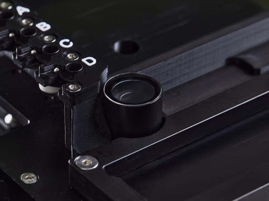 Close-up of a black machine vision camera lens integrated into industrial equipment with labelled connectors.