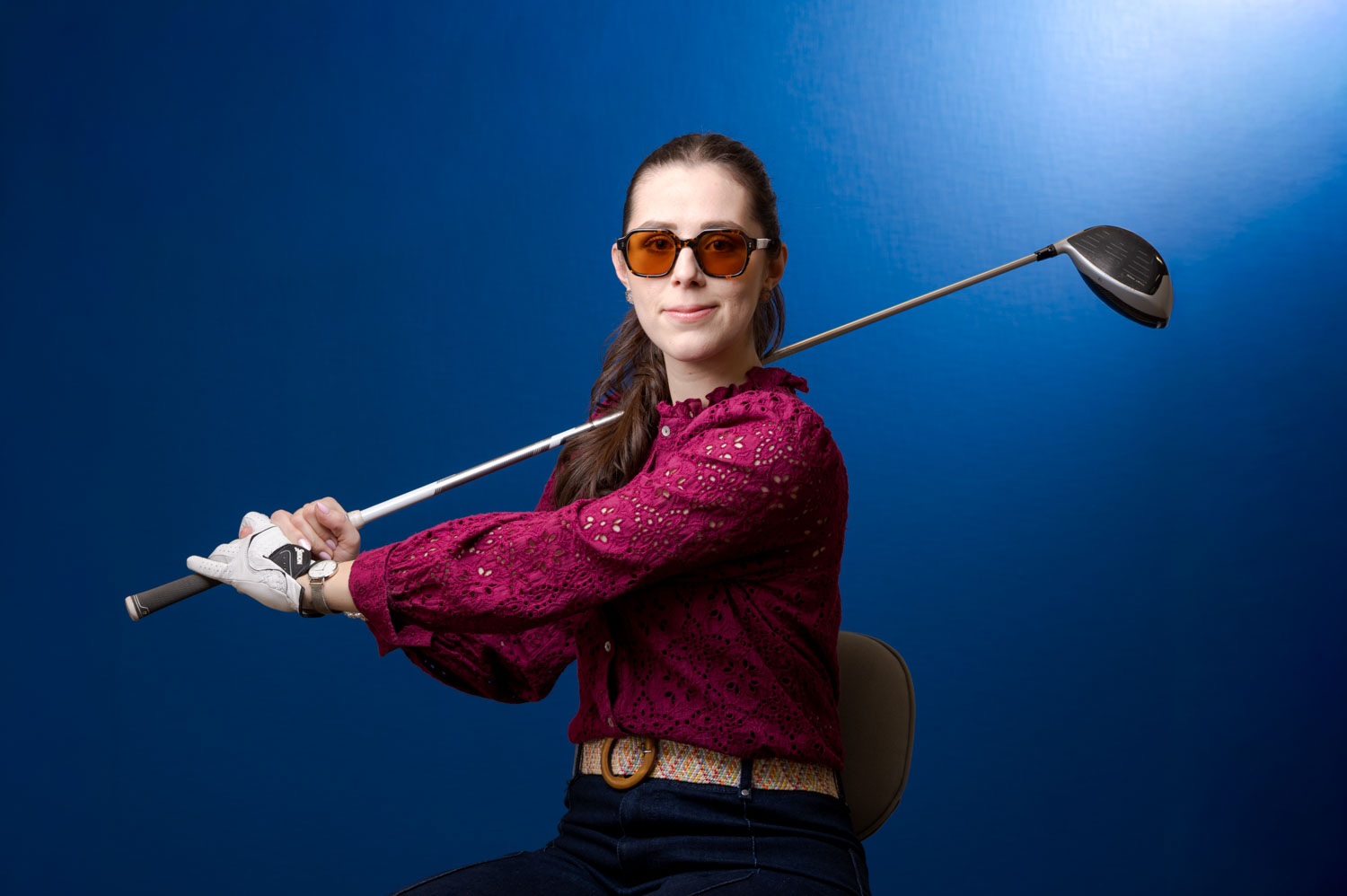 portrait ludique avec fond bleu avec une femme qui joue au golf dans son bureau 