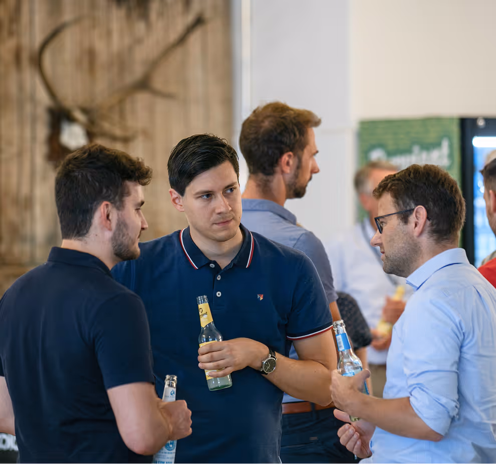 Ninox CFO Daniel, talking to two other guys while drinking a beverage