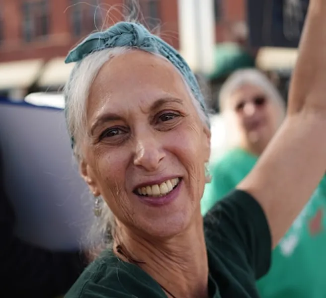 Smiling older woman raising her arm during an outdoor gathering
