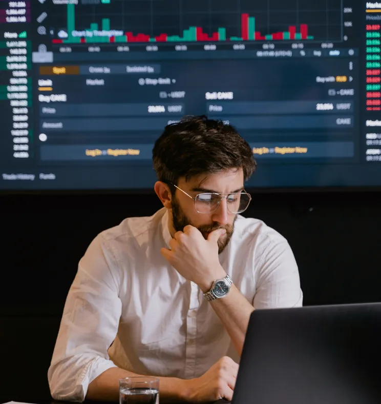 Man analyzing data on a laptop with charts displayed behind him