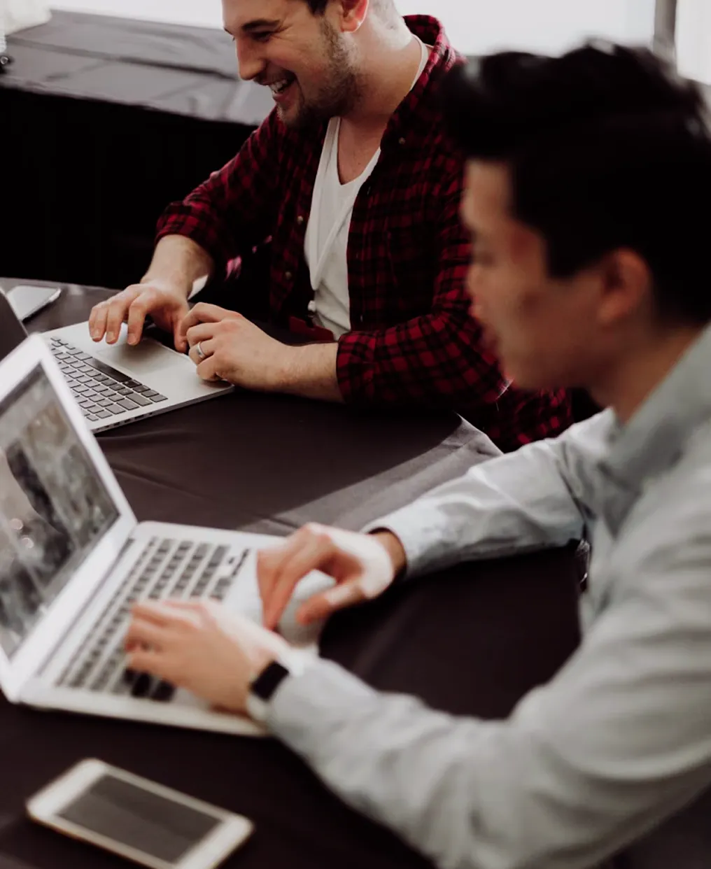 Two coworkers collaborating on laptops at a table