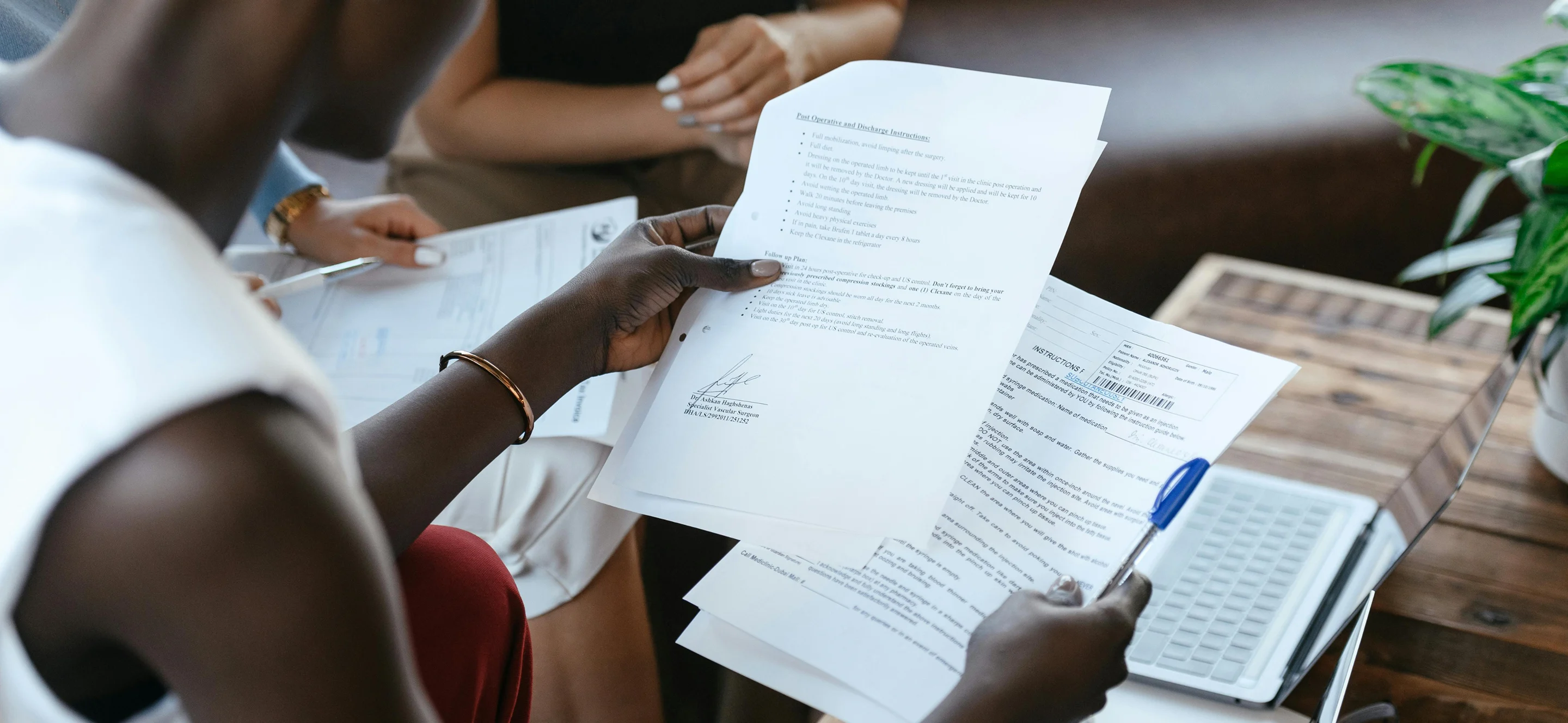 People reviewing printed documents together near a laptop