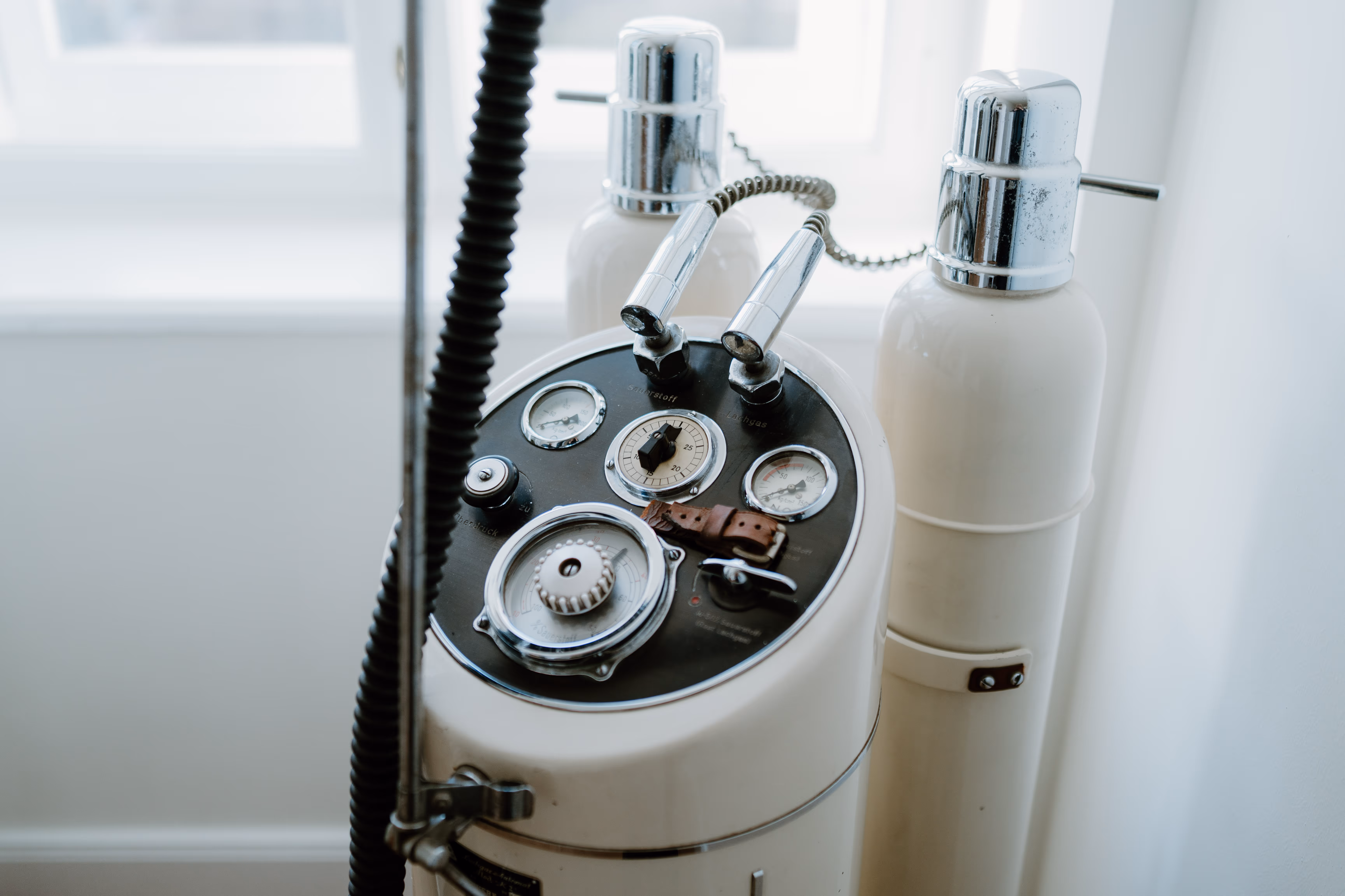 Nahaufnahme eines medizinischen Geräts mit Druckmessern und Schläuchen vor einem Fenster.