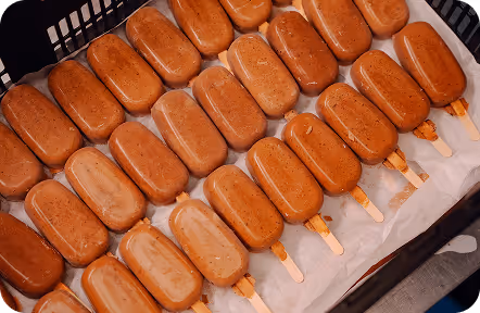Man in black hoodie working on a laptop displaying a graphic design software at a desk in an office at Tecbot.