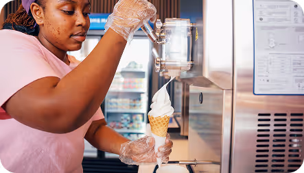 Man in black hoodie working on a laptop displaying a graphic design software at a desk in an office at Tecbot.