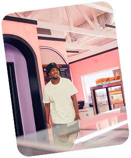 Person dispensing soft serve ice cream into a cone from a machine.