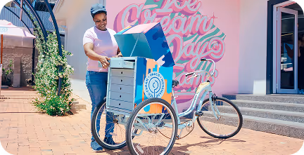 Man in black hoodie working on a laptop displaying a graphic design software at a desk in an office at Tecbot.