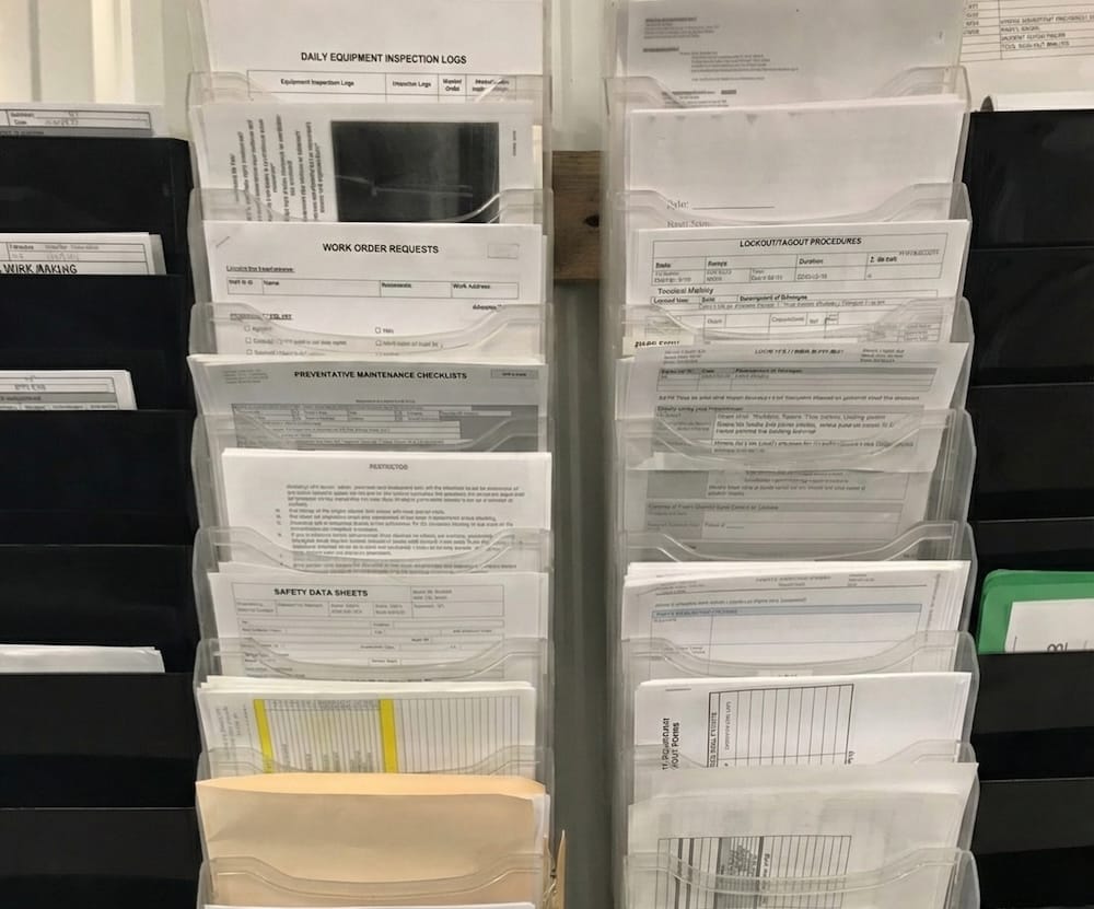 A wall of maintenance forms in plastic holders