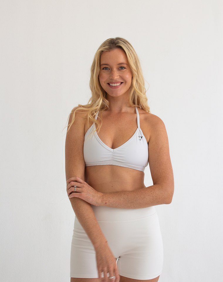 Woman in blue sportswear performing side plank exercise on a yoga mat indoors near a colorful wall painting.