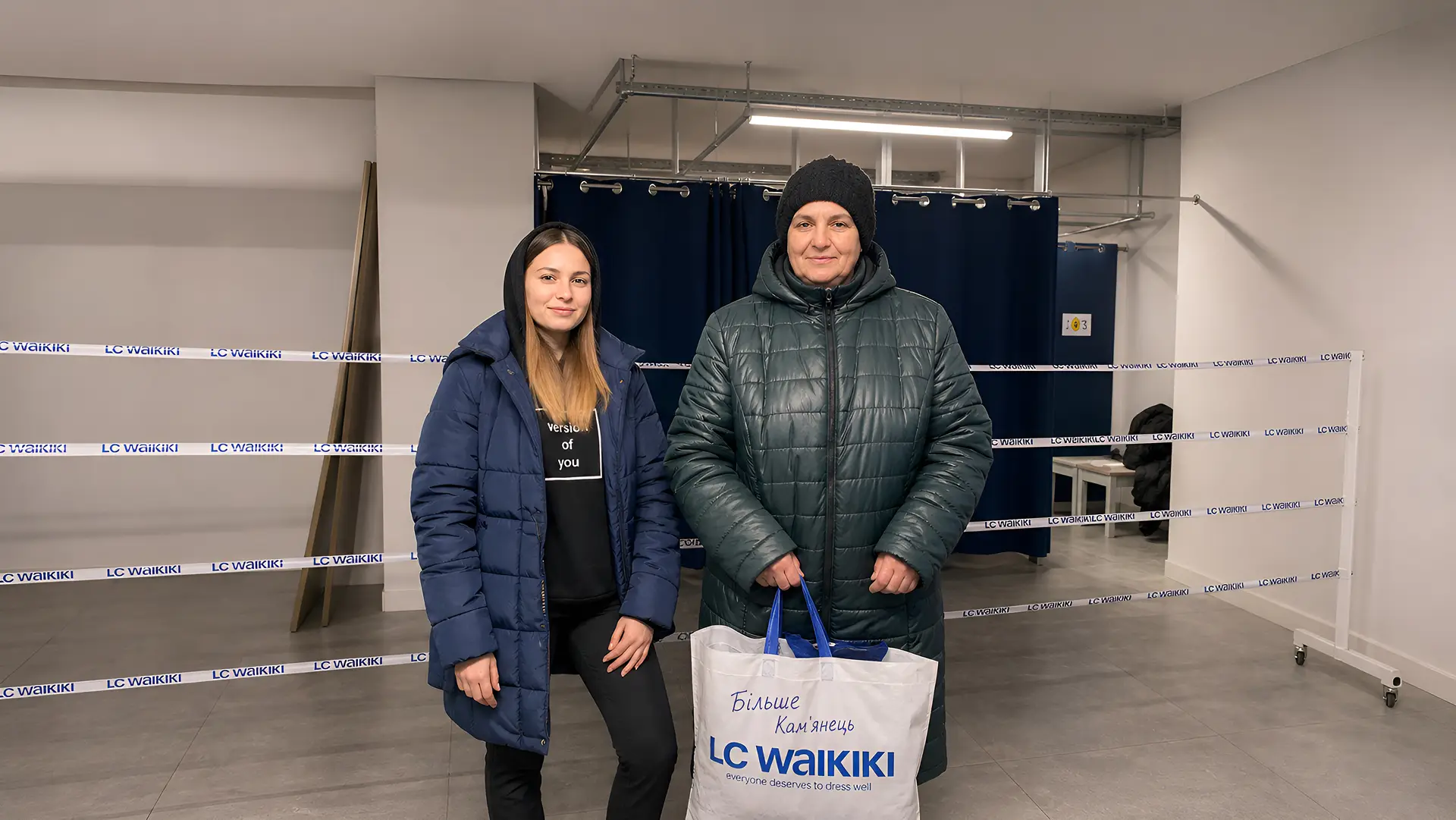 Дівчина та жінка у зимових куртках з пакетом одягу в магазині.