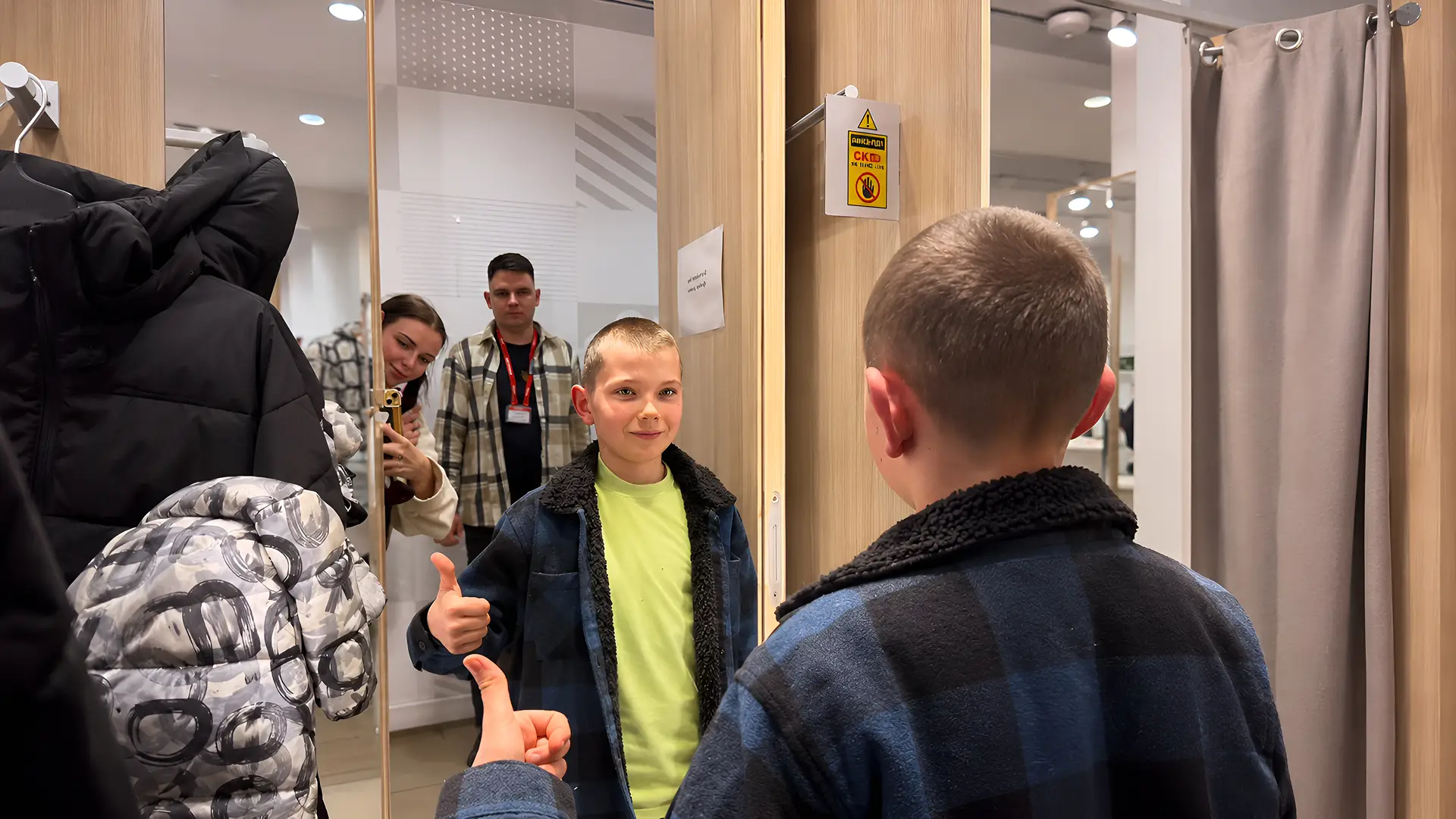 Хлопчик показує новий зимовий одяг у примірочній.
