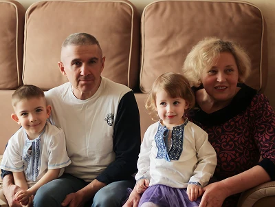 Родина з двома дітьми сидить разом на дивані.