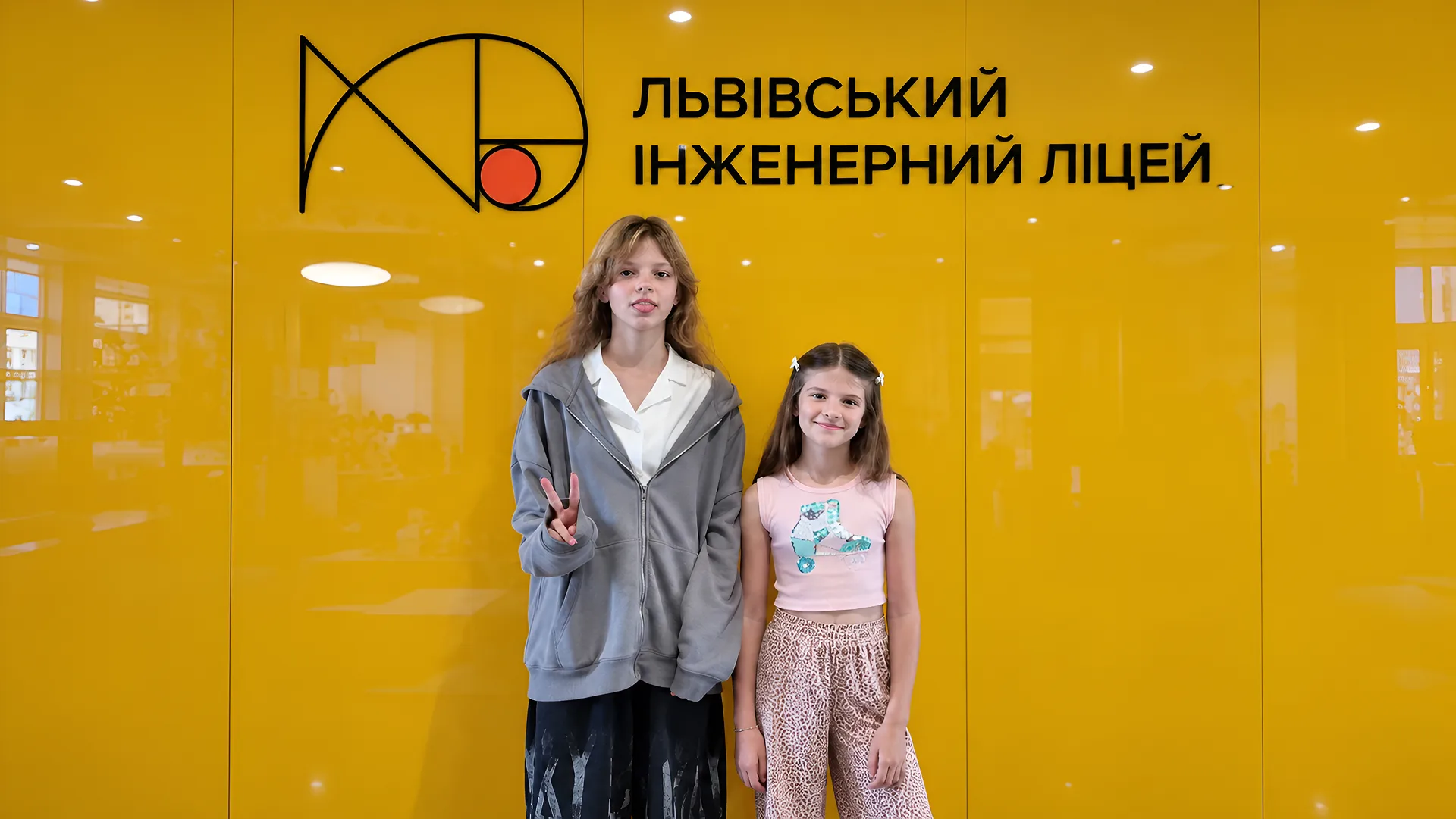 Дві дівчини позують біля логотипа Львівського інженерного ліцею.