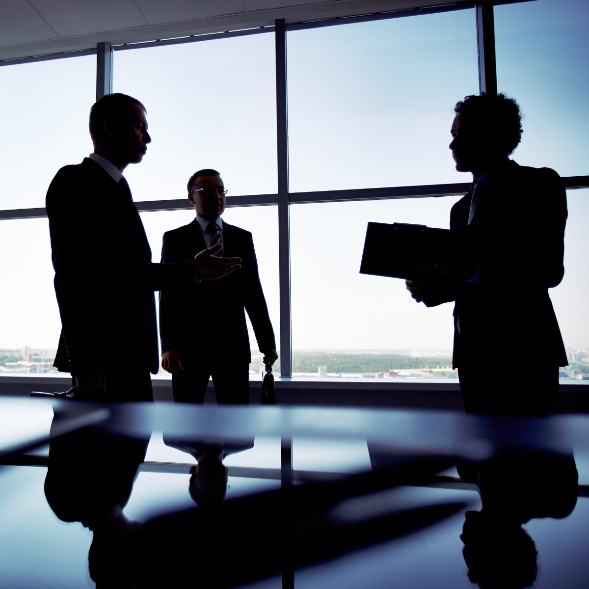 Silhouetten von Geschäftsleuten im Gespräch vor Fensterfront
