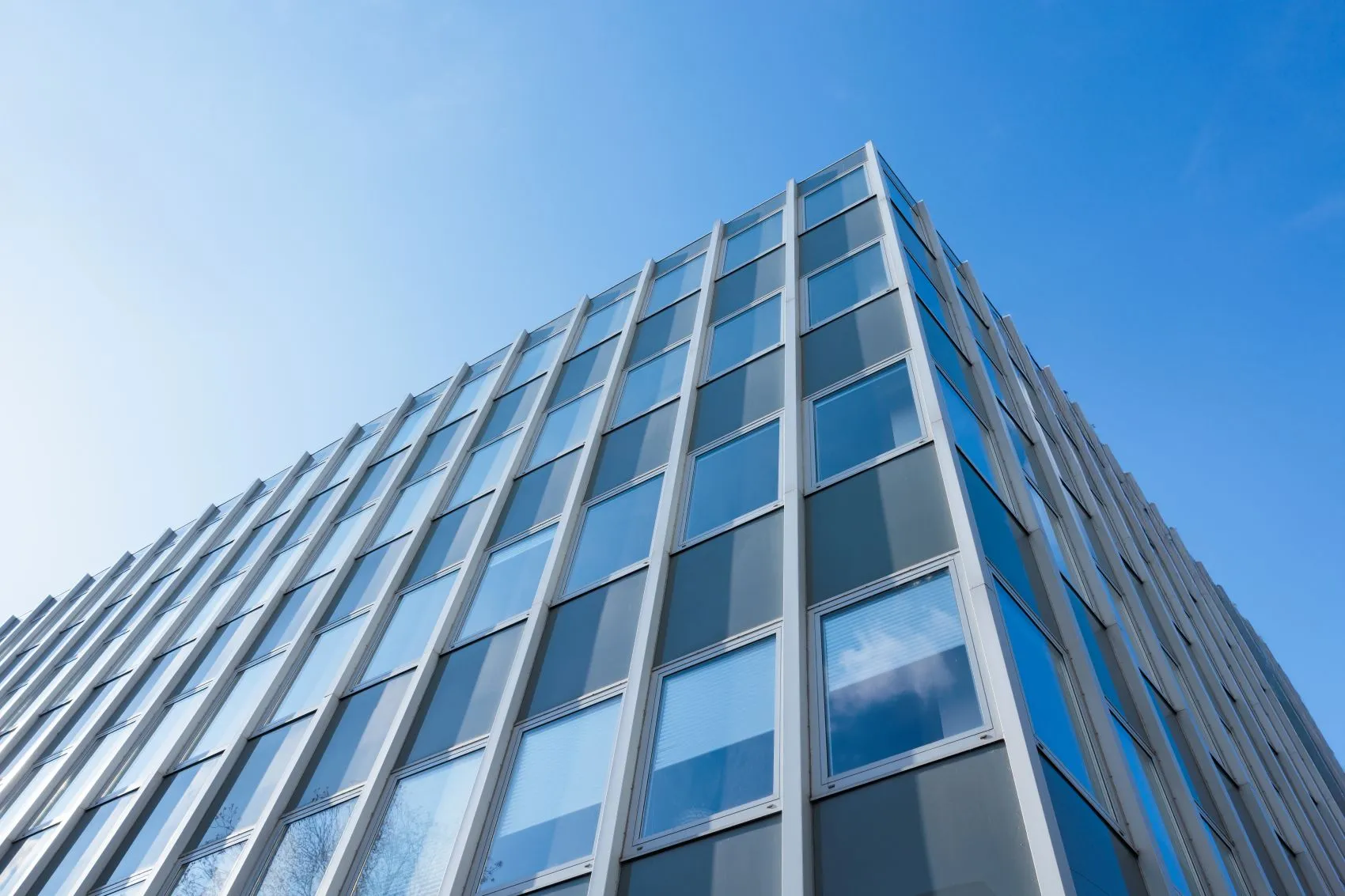 Blick nach oben auf ein modernes Hochhaus mit Glasfassade
