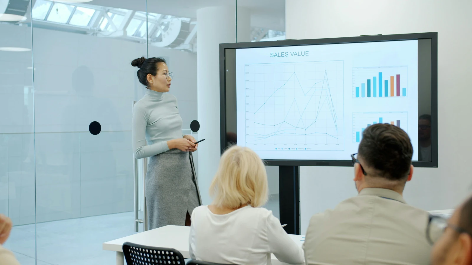 Consultante présentant les métriques de performance et ROI à des clients en salle de réunion