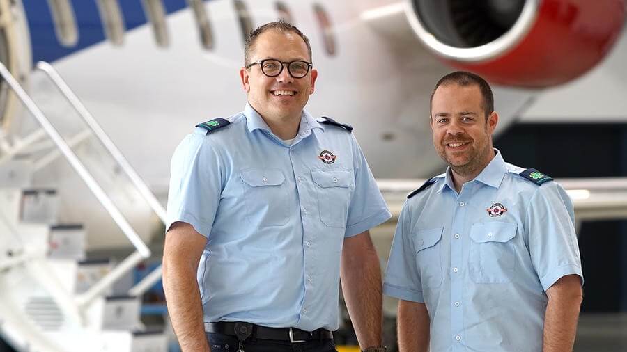 European Air Ambulance crew members standing in front of a medical aircraft inside a hangar.