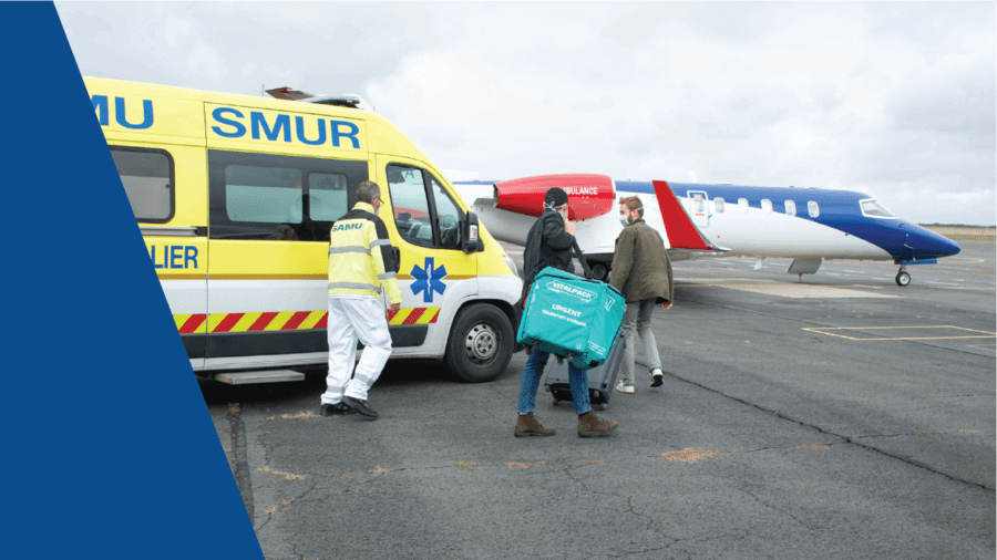 Medical team transferring equipment from an ambulance to a European Air Ambulance aircraft on the airport apron.