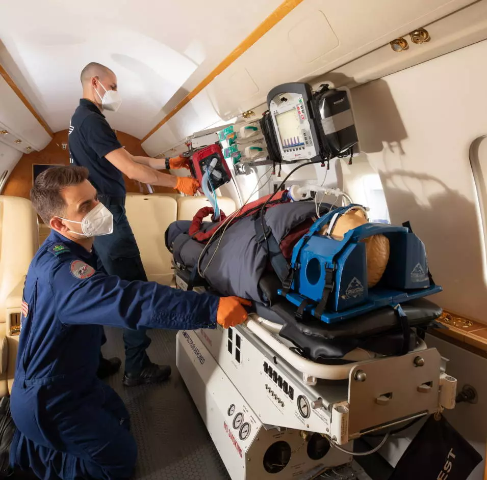 Medical team treating a patient on a stretcher inside a European Air Ambulance aircraft equipped for intensive care transport.