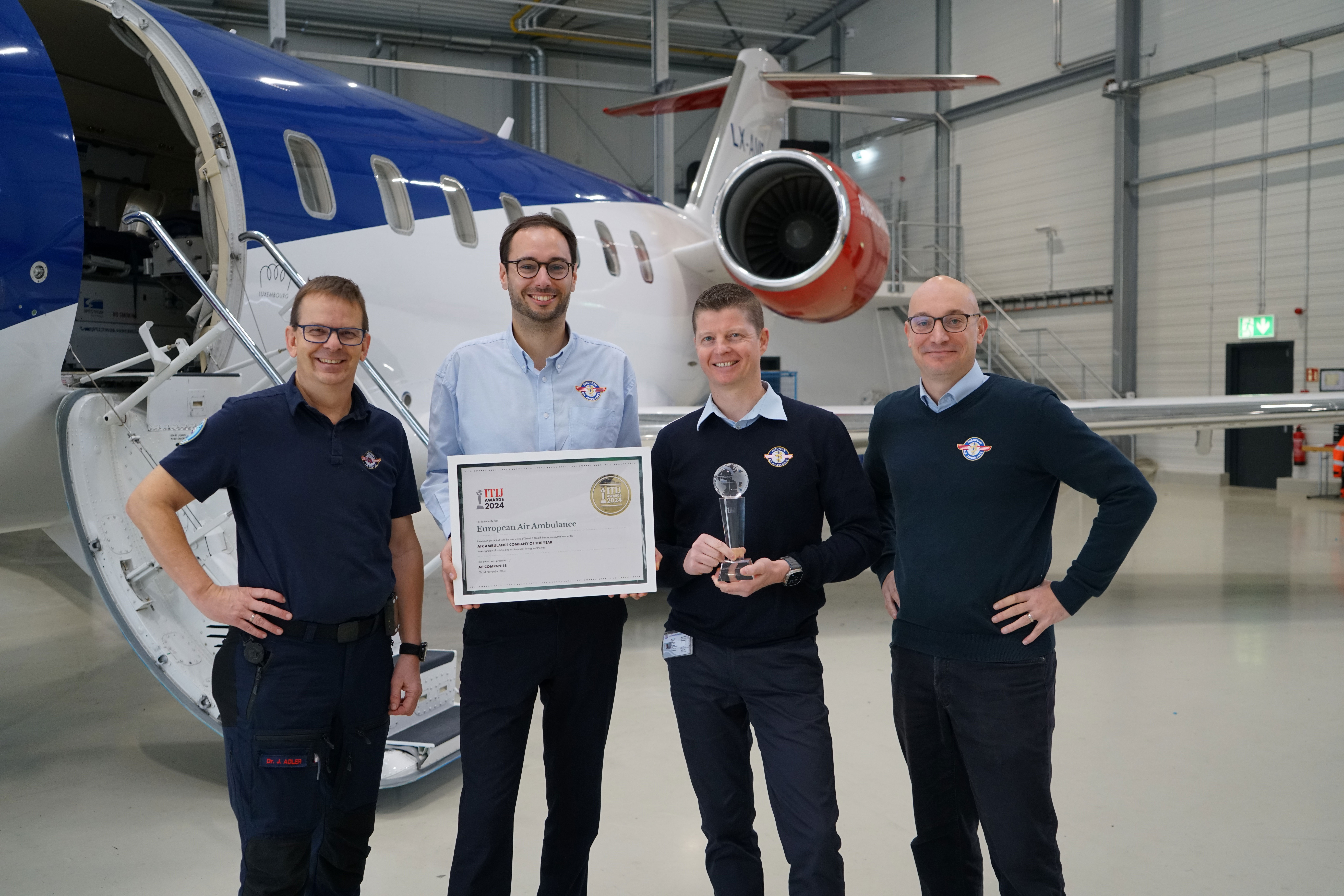 European Air Ambulance team receiving the Air Ambulance Company of the Year award in front of a medical aircraft.