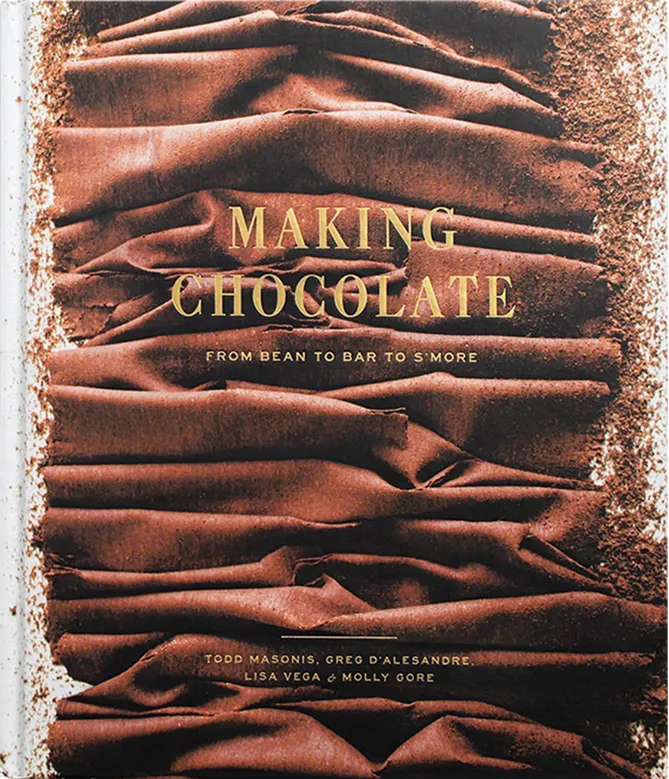Cover of a book titled 'Making Chocolate: From Bean to Bar to S'more' surrounded by folds and powder of dark chocolate.