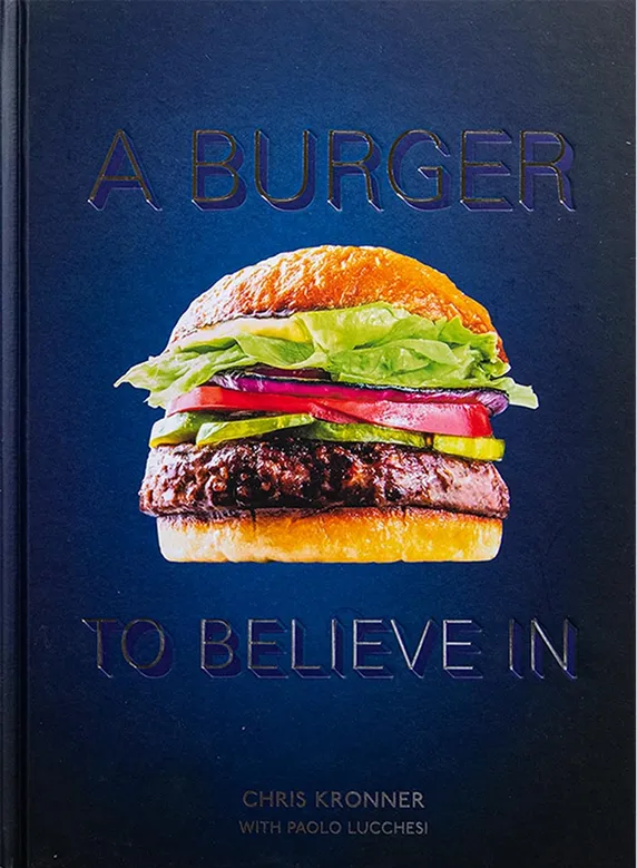 Book cover titled 'A Burger to Believe In' showing a hamburger with lettuce, tomato, pickles, and beef patty on a blue background.