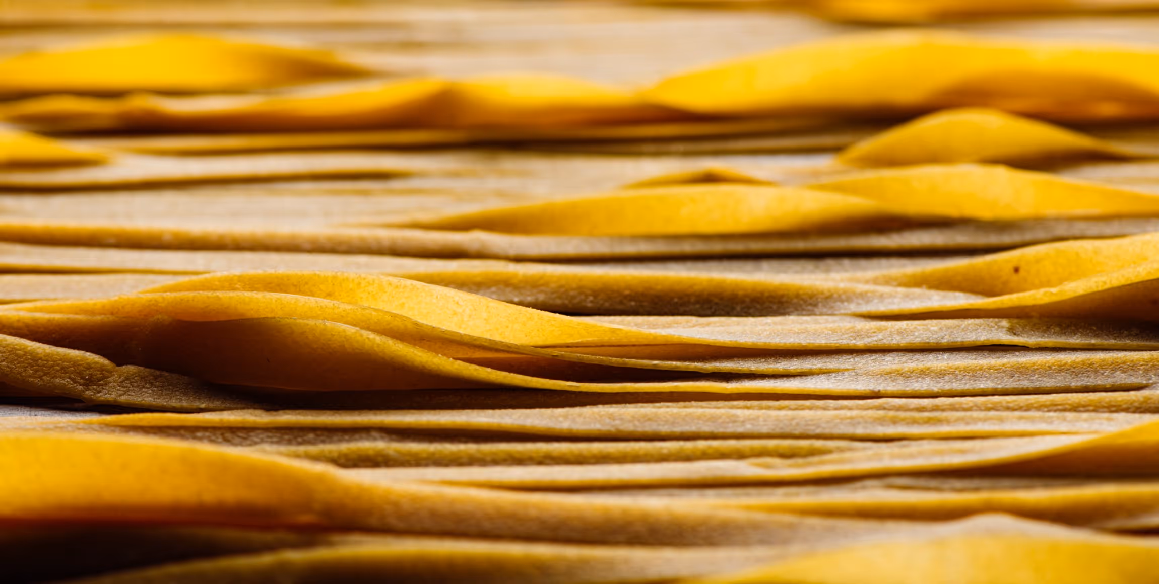 Close-up of uncooked fresh yellow pasta sheets layered closely together.