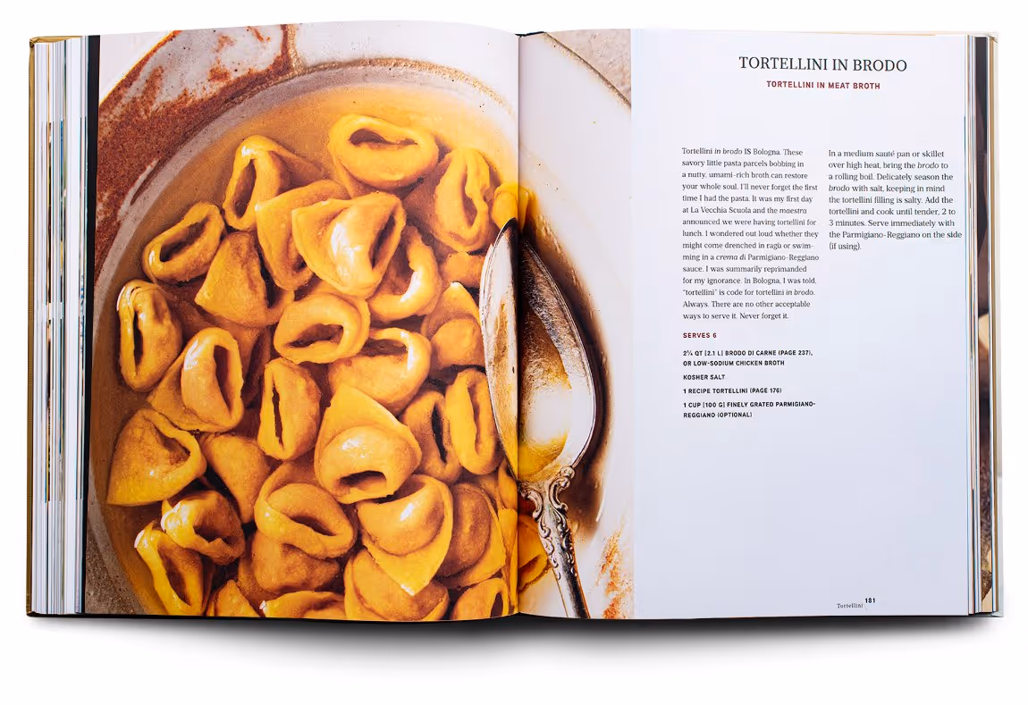 Open cookbook showing a photo of tortellini pasta in broth on the left page and a tortellini in meat broth recipe with cooking instructions on the right page.