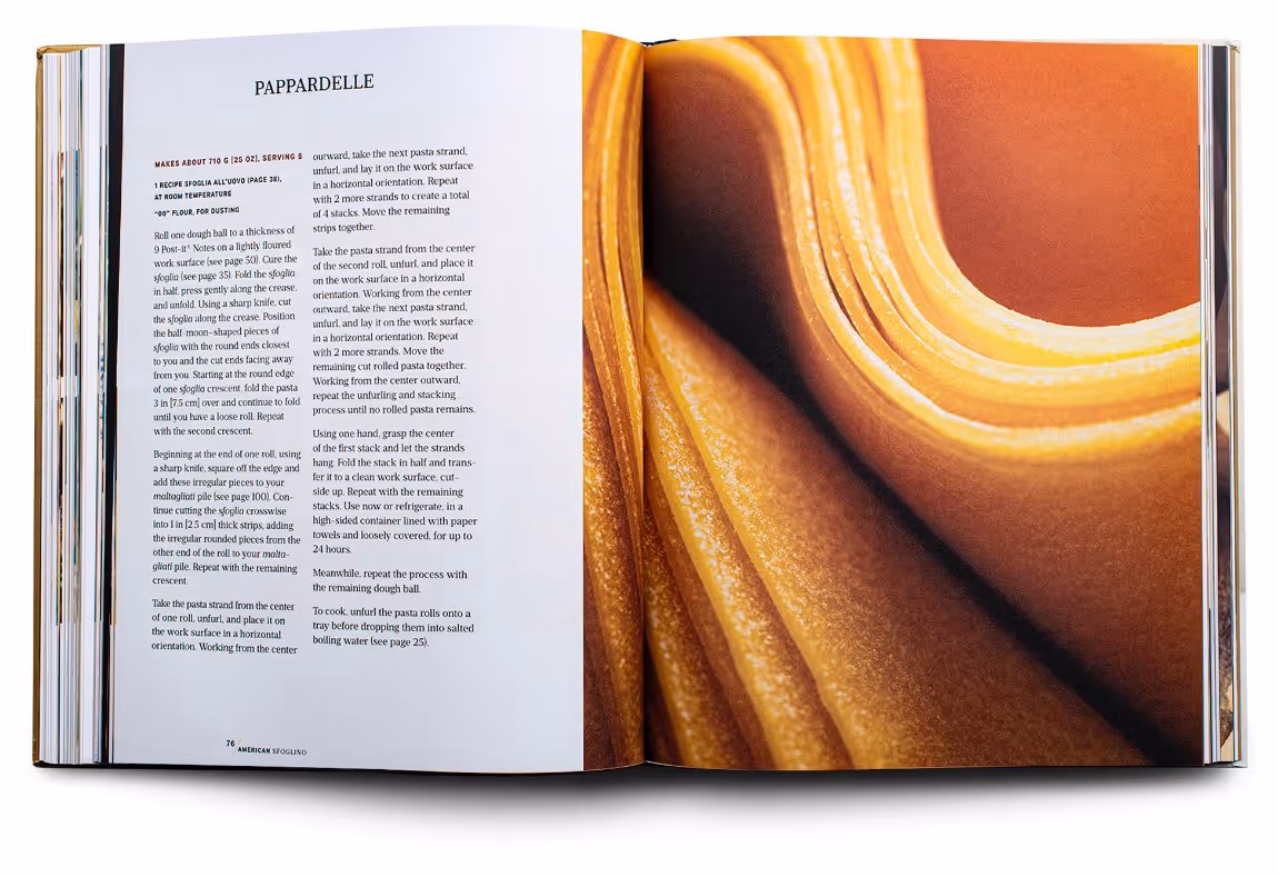 Open cookbook showing a Pappardelle pasta recipe on the left page and a close-up image of folded pasta dough on the right page.