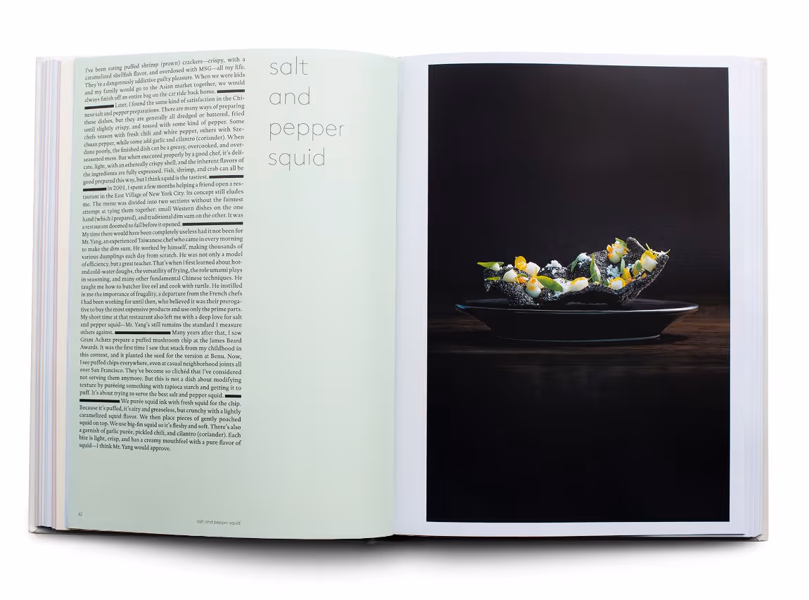 Open cookbook displaying a page titled 'salt and pepper squid' with text on the left and a dark plate with a modern squid dish on the right.
