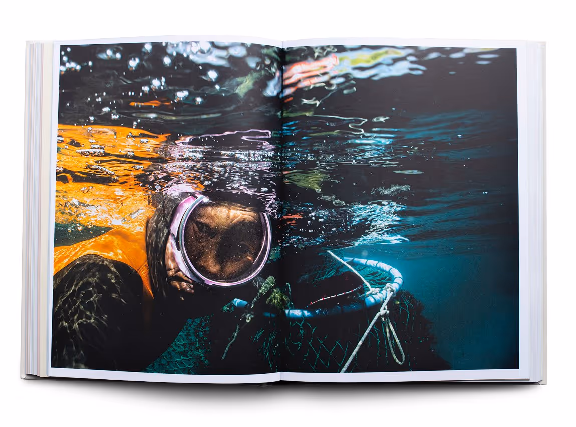 Open book with a photo of a snorkeler underwater next to a fishing net or cage.