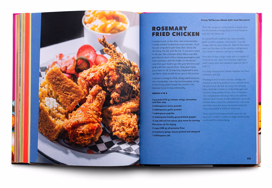 Open cookbook showing a plate of fried chicken wings with cornbread and sliced pickles on the left page and a rosemary fried chicken recipe text on the right blue page.