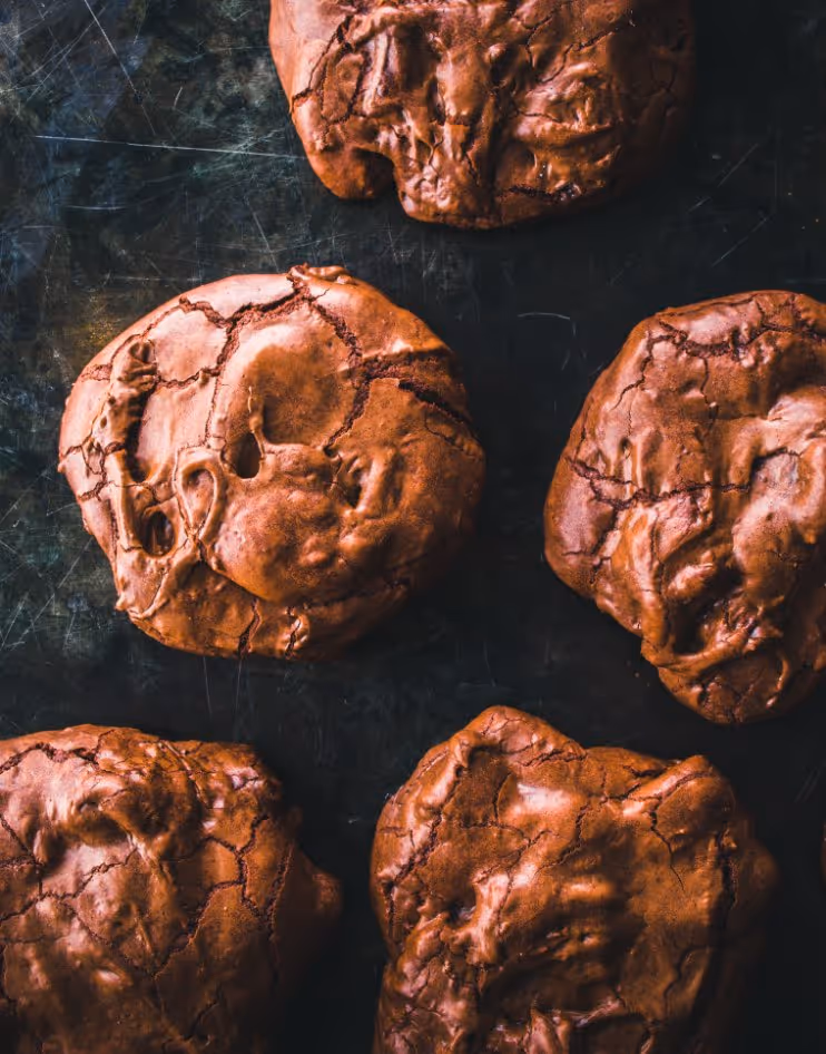 Close-up of five cracked chocolate cookies on a dark surface.