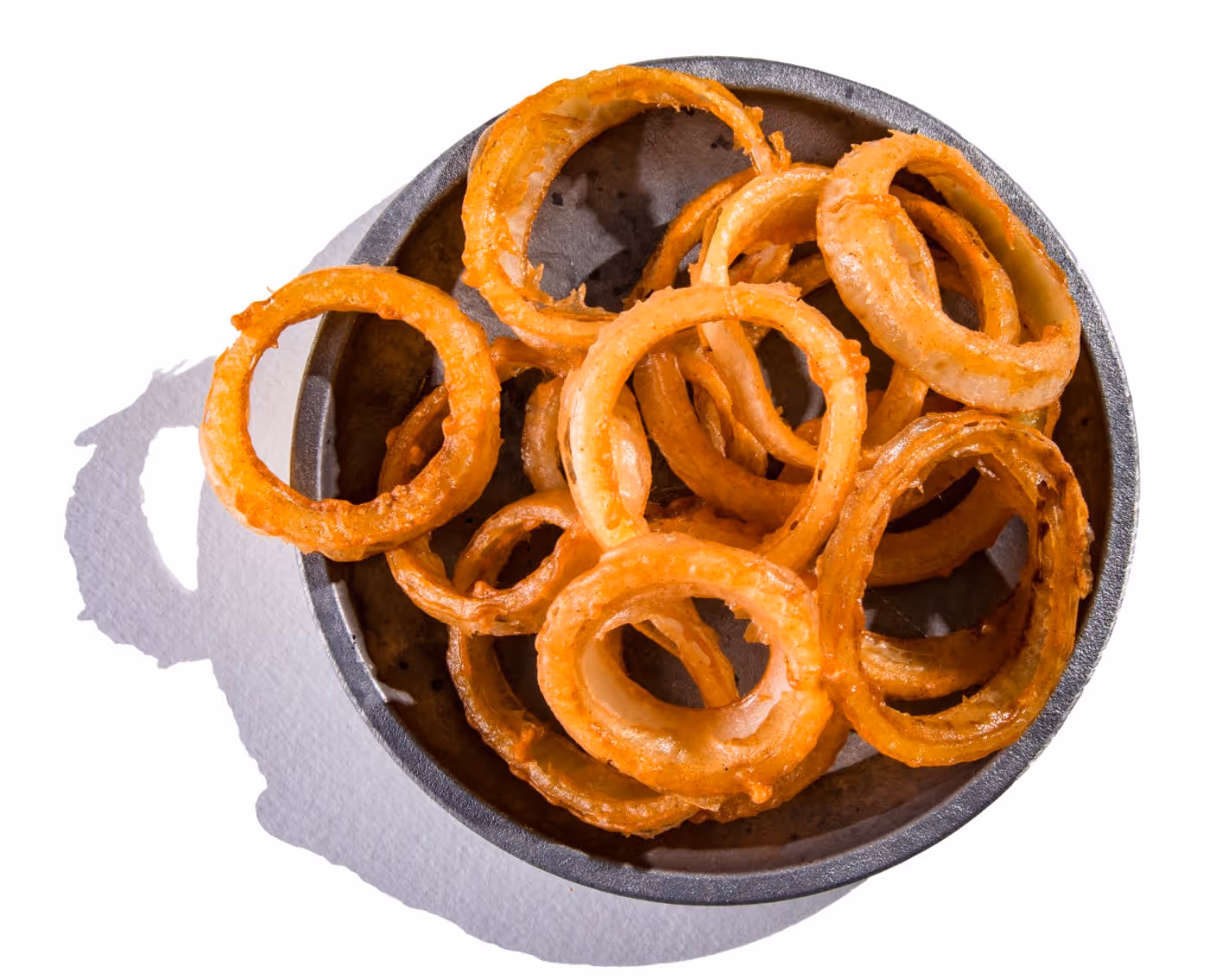 Golden-brown crispy fried onion rings in a dark bowl on a white surface.