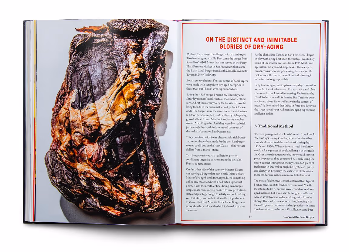Open book showing a large image of a dry-aged beef cut on the left page and text titled 'On the Distinct and Inimitable Glories of Dry-Aging' on the right page.