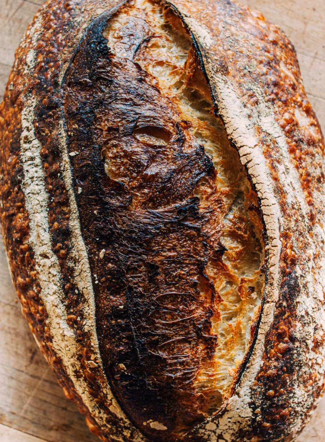 Close-up of a crusty loaf of artisan bread with a dark, cracked crust and rustic texture.