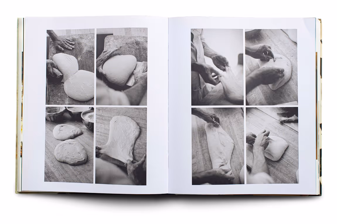 Open book showing black and white photos of hands shaping and stretching bread dough on a wooden surface.