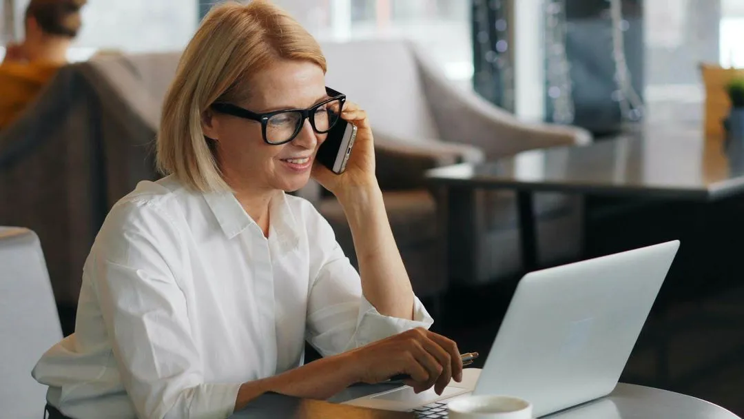 A woman wearing glasses and a white shirt is using a laptop.