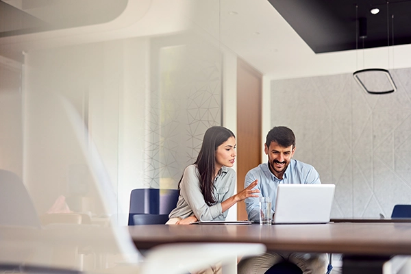 Two colleagues reviewing documents on a laptop in an office