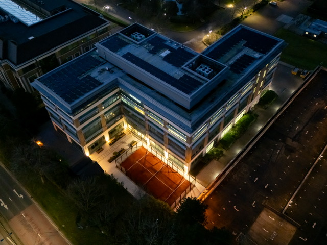 dark red padel court shown from above at night time