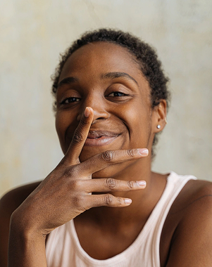 Une femme souriante, la main près du visage.