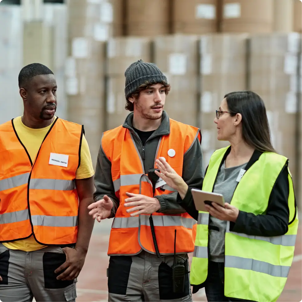 warehouse workers with goods stacked in background