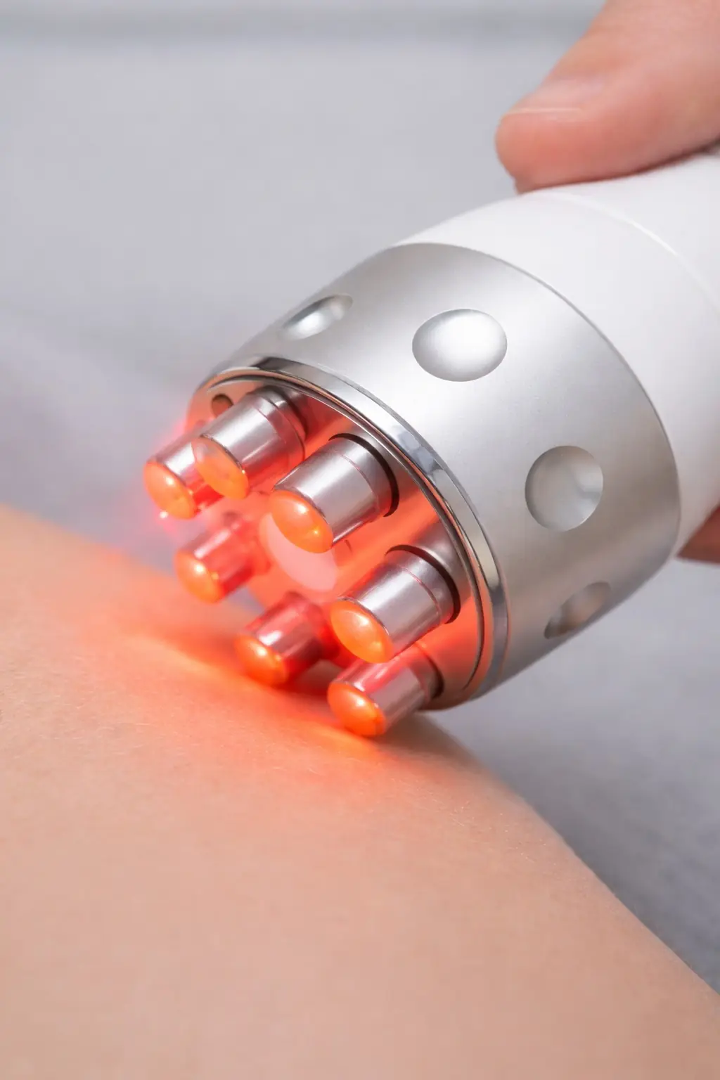 Gros plan d'un applicateur de radiofréquence émettant une lumière rouge lors d'un traitement sur la peau.