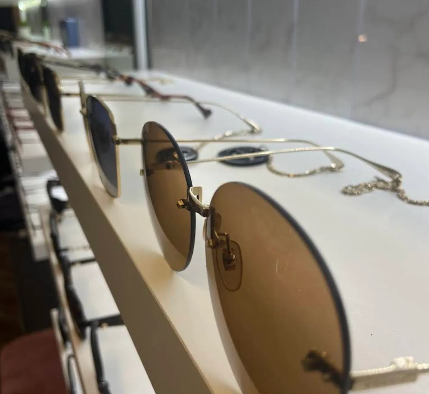 Row of sunglasses with brown lenses and metal frames displayed on white counter