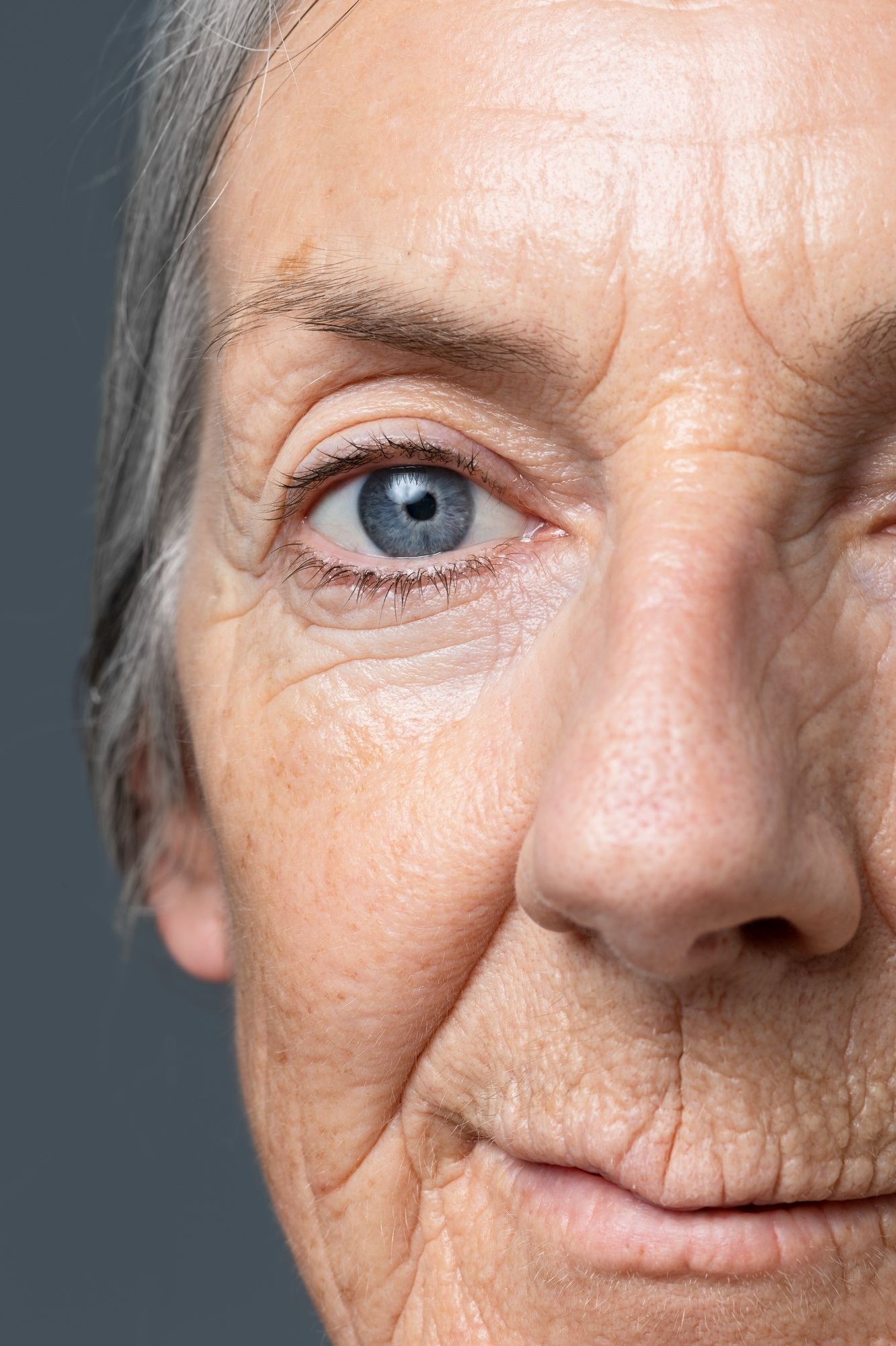 Close-up of elderly person's wrinkled face with blue eye visible